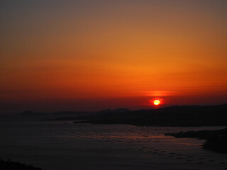 Fototapeta premium Sunset in the sea with coast and the islands in the background