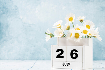 cube calendar for July with daisy flowers over blue