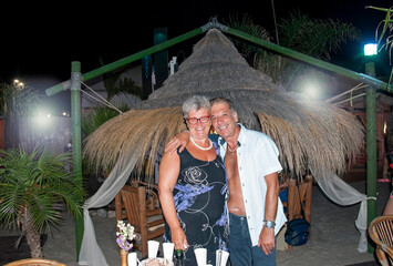 Caucasian elderly couple posing embraced for a portrait at a night party. Anniversary.
