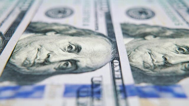 Macro footage of hundred American dollars arranged in row, focus on portrait of Benjamin Franklin. Tracking shot of cash money symbolizing success. Concept of finance