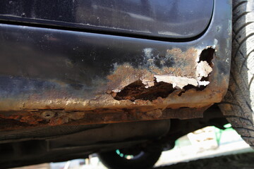 Through corrosion of the car door sill closeup, rust hole in vehicle body after winter