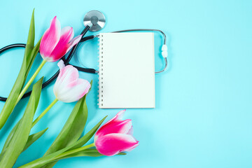 Pink tulips and stethoscope with spiral notepad