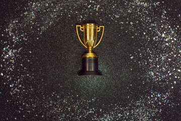 One Golden winner cup with silver sparkles on a black background.