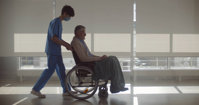 Nurse Wearing Face Medical Mask Pushing Wheelchair With Senior Man Patient