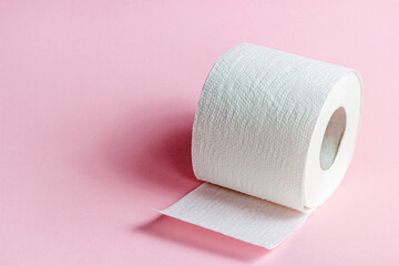 White toilet paper roll on light pink background with copy space.