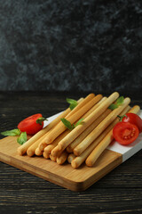 Board with grissini breadsticks on wooden table