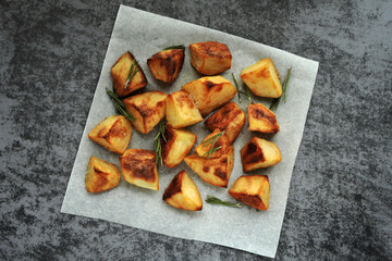 Baked potatoes in pieces on paper. Appetizing French fries.