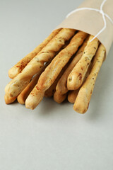 Craft paper with grissini breadsticks on light gray background