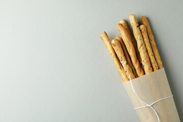 Craft paper with grissini breadsticks on light gray background