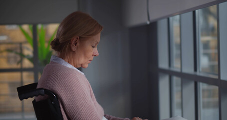 Sad handicapped elderly woman seated in wheelchair crying