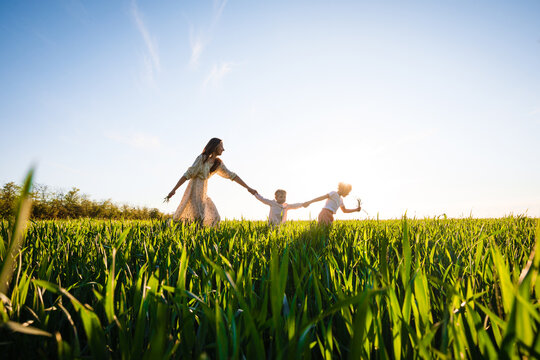 A mother with two daughters is walking in a green field. Hugs and feelings.