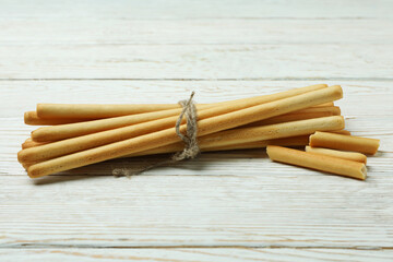 Tasty grissini breadsticks on white wooden background