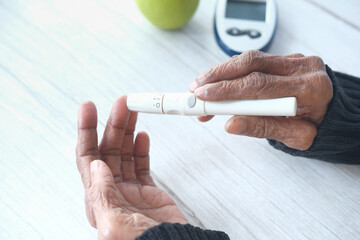 Senior women diabetic measure glucose level at home 