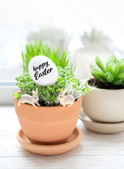 Cute rabbits, easter egg and cress-salad in pot. easter table decoration idea. festive spring season.
