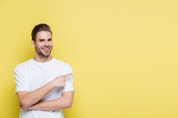 cheerful man looking at camera while pointing with finger on yellow