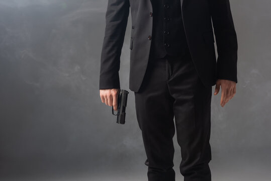 partial view of armed businessman on grey background with smoke