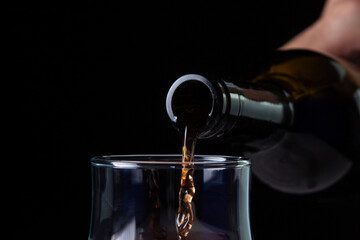 Wine is poured into a glass close-up. Wine on a black background. Red wine on a dark background. Alcoholic drink