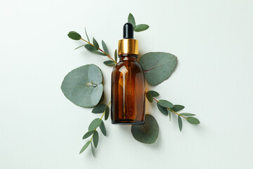 Dropper bottle of eucalyptus oil and leaves on white background