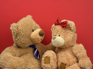 two brown teddy bears sitting opposite each other on a red background