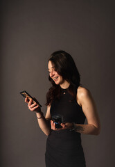 Cheerful girl holds her mobile phone and a bluetooth speaker choosing her music while smiling