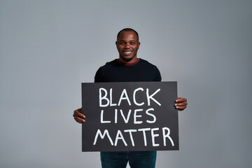 Happy african american man holding anti racism poster