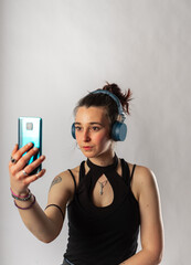 Alternative girl with tattoo using her cell phone and wireless headphones wearing a sleeveless topAlternative girl with tattoo using her cell phone and wireless headphones wearing a sleeveless top. 