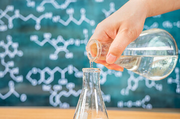 Laboratory glassware with blackboard background with various chemical formulas.