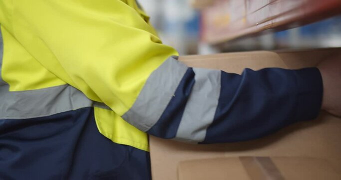 Close up of warehouse worker putting cardboard box on shelf