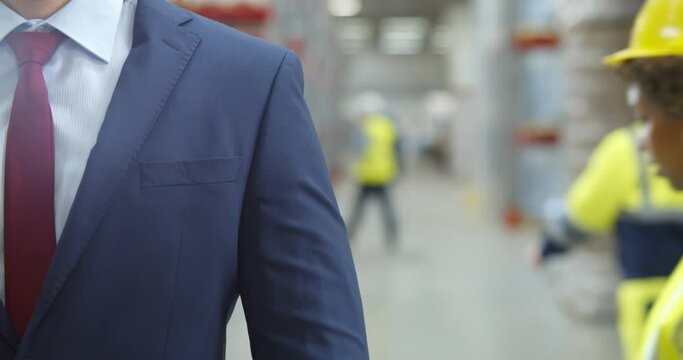 Cropped shot of businessman adjusting tie standing in warehouse