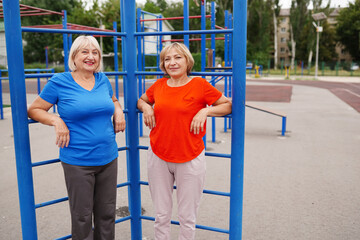 two adult women 58 and 64 years old doing exercises outdoors on the stadium