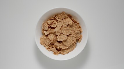 Fitness flakes in a white dish on a white table, Top view - 424169333