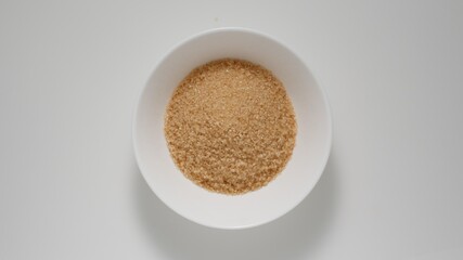 Brown sugar in deep dish on a white table, Top view - 424169358