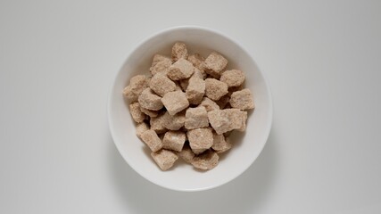 Cubes of brown sugar in white deep dish, Top view