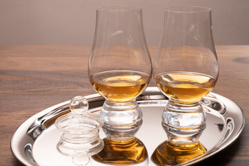 Tasting glasses of single malt scotch whisky served on steel mirror tray with reflection