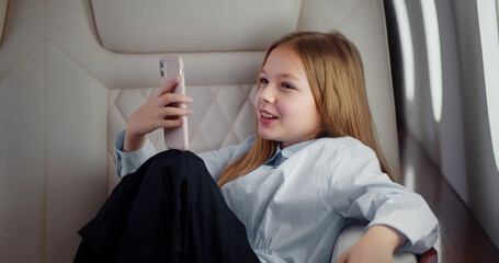 Fototapeta premium Kid with mobile phone in airplane in window seat.