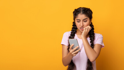 Worried scared indian woman looking at phone seeing bad news