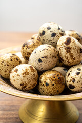 Fresh small spotted partridge eggs on bronze plate
