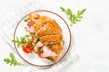 Croissant sandwich on white table.