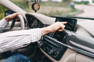 Modern car, man's hand reaches for the screen in the car to turn on the navigator