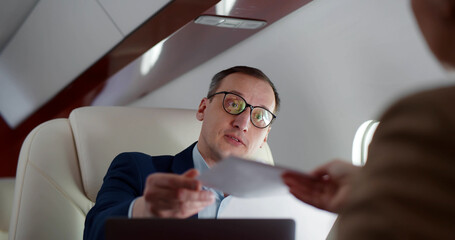 Successful businessman and businesswoman reading and discussing documents flying on private jet