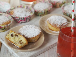 Obraz na płótnie Canvas Freshly baked homemade raisin muffins in paper tins on a wooden background with raspberry juice.