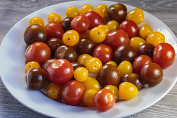 Multicolored tomatoes of different varieties in a dish. Fashionable vegan food.