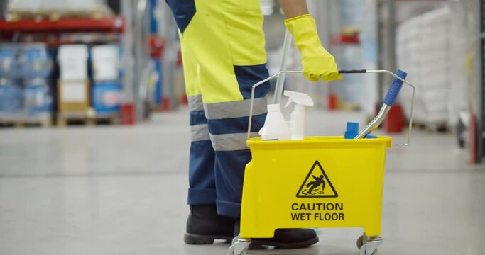 Cropped shot of janitor with bucket washing floor in warehouse