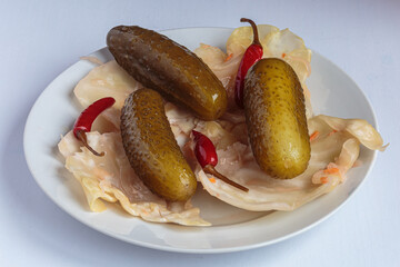 Delicious pickles-sauerkraut, salted cucumbers and pickled hot pepper on a platter. Concept of healthy snack. Vegan food.