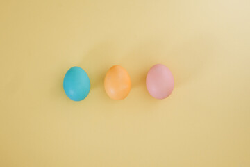 Painted Easter eggs in pastel colors yellow blue pink on a trendy yellow background. Creative minimalistic Easter background. Flat lay, top view