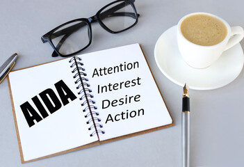 AIDA. text on white paper on gray background. text on white notepad paper. near cups with coffee and plants on a gray background.