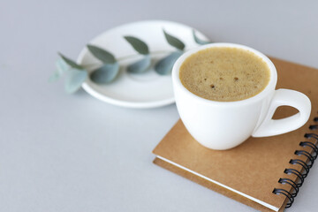 white cup and saucer on gray background with notepad