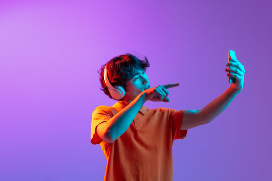 Young Man Talking On Phone Isolated Over Pink Purple Background In Neon Light