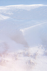Top view of the snow-covered hill in the tundra. Snow with mud and long shadows