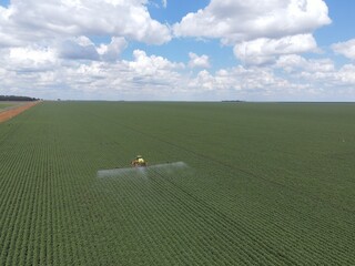 Imagem aérea de ambiente agrícola durante pulverização da lavoura.